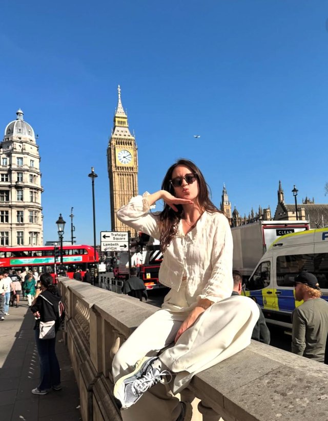 A woman sitting on a stone wall with Big Ben in the background
